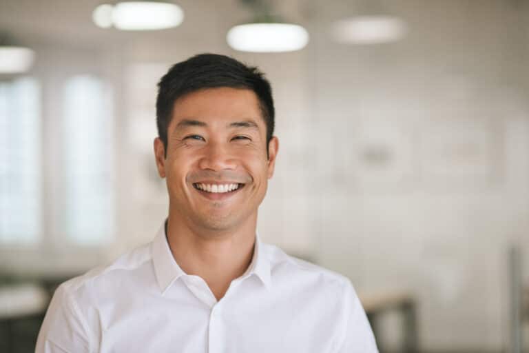 Well,Dressed,Young,Asian,Businessman,Smiling,Confidently,While,Standing,Alone
